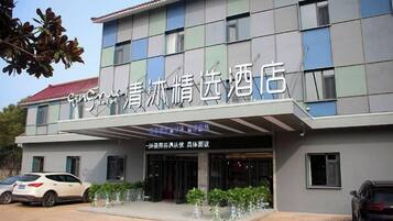 A hotel with a modern facade, a covered entrance, and a parking area with cars.