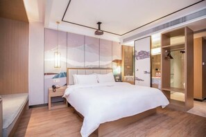 A modern hotel room with a large bed, a bedside table, a nightstand, a wardrobe, and a mirror. - Qingmu Select Hotel (Liyang Tianmu Lake Scenic Area) (Liyang)