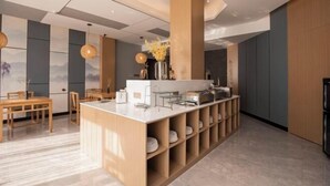 A modern kitchen with a central island, wooden cabinets, and a dining area with a table and chairs. - Qingmu Select Hotel (Liyang Tianmu Lake Scenic Area) (Liyang)