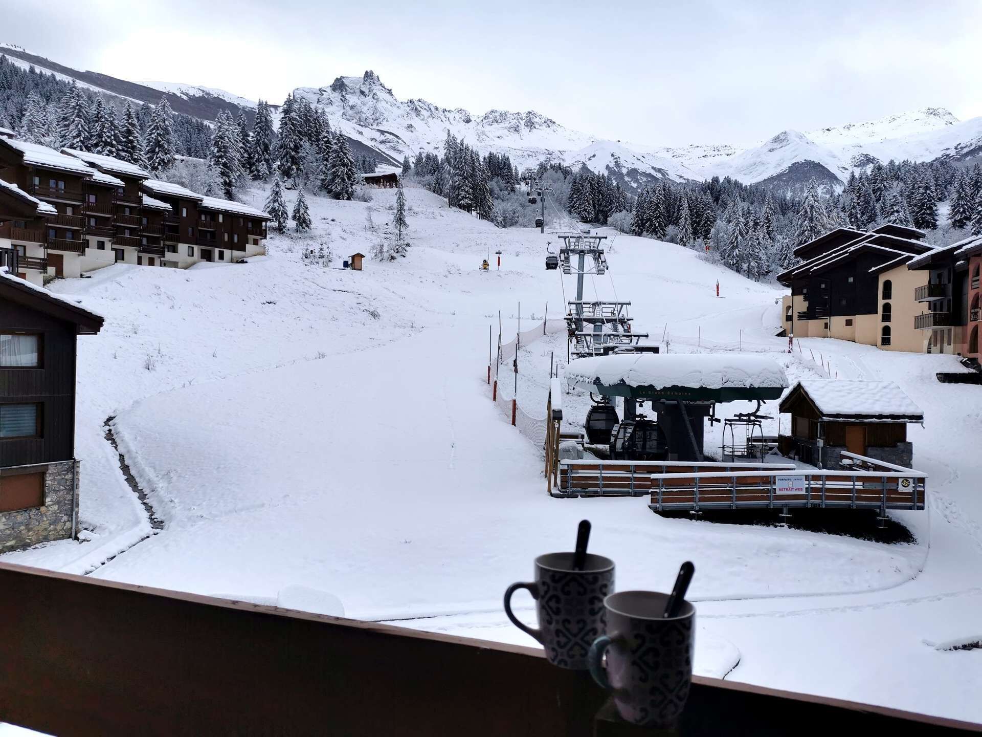 A snow-covered mountain resort with ski lifts, wooden buildings, and a snowy landscape.