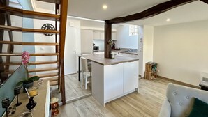 A modern kitchen with a central island, wooden beams, and a dining area with a table and chairs.