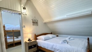 A bedroom with a bunk bed, a bedside table with a lamp, and a bed with neatly folded towels.