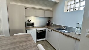 A compact kitchen with a microwave, oven, sink, and a window above the countertop.