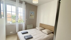 Une chambre à coucher avec un lit, une fenêtre avec des rideaux, un radiateur et un tableau accroché au mur.