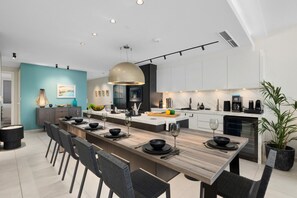 A modern kitchen with a central island, white cabinets, and a teal accent wall.