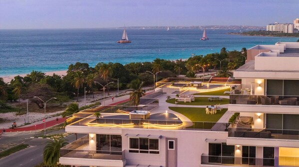 A modern hotel with a rooftop terrace overlooking a beach and the sea.