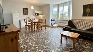 A compact living space with a dining area, a sofa, and a kitchen.