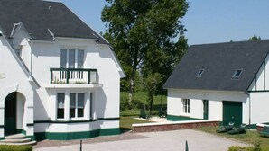 A white building with a green roof and a balcony, surrounded by trees. - La pommeraie 4, apartment for 4 people (Quend)