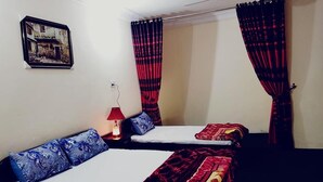 Una habitación con dos camas, una lámpara roja y un cuadro en la pared.