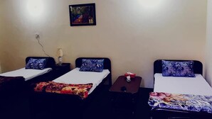 Habitación con dos camas individuales, cada una con almohada y mesita de noche. Cuenta con ventilador de techo y un cuadro en la pared.