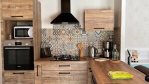 Eine Küche mit Holzausstattung, einem Bosch-Ofen, einem Gasherd und einer ornamental gestalteten Spritzschutzleiste.