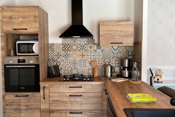 A kitchen with wooden cabinets, a Bosch oven, a gas stove, and a patterned backsplash.