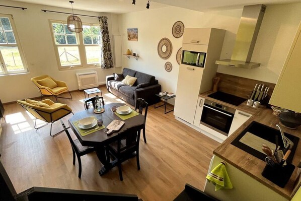 A modern apartment with a dining area, sofa, kitchen, and large windows. - La Cabarette, country gîte for 4 people (Arry)