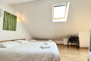 A bedroom with a bed, a chair, a window, and a wall art piece. - Gîte 4, 3-person gîte in the center of town (Le Crotoy)