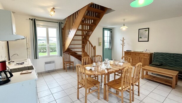A modern kitchen with a wooden staircase, a dining area with wooden chairs, and a green sofa. - Les Eglantines 3, superb apartment (Fort-Mahon-Plage)