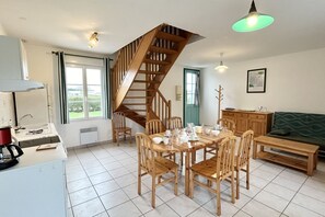 Eine moderne Küche mit einer Holztreppe, einem Essbereich mit Holzstühlen und einem grünen Sofa.
