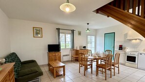 A cozy living room with a sofa, a TV, and a dining area with chairs and a table. - Les Eglantines 3, superb apartment (Fort-Mahon-Plage)