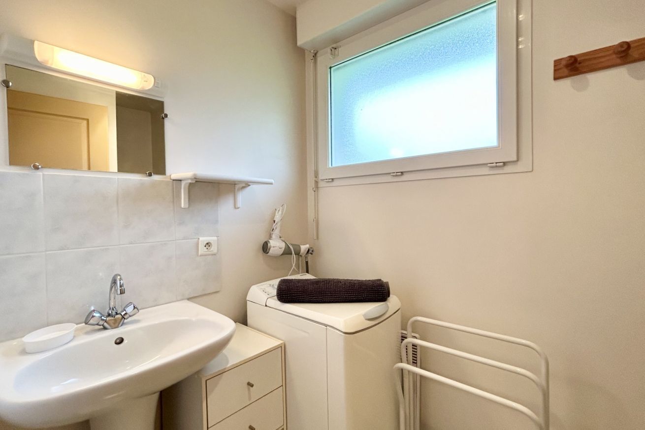 Un bagno con lavandino, specchio, portasciugamani e finestra.