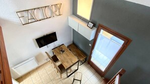 Una habitación con una mesa de madera, una televisión, una ventana y un letrero en la pared.