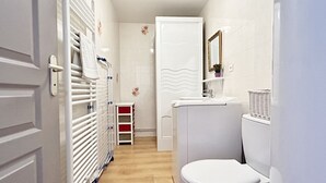 Une petite salle de bain comprenant des toilettes, un lavabo, un miroir et un porte-serviettes.