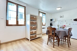 Een keuken met een eettafel, stoelen, een kast met manden en een magnetron.
