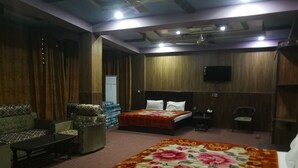 Une chambre d’hôtel avec deux lits, un canapé, un fauteuil et une télévision.