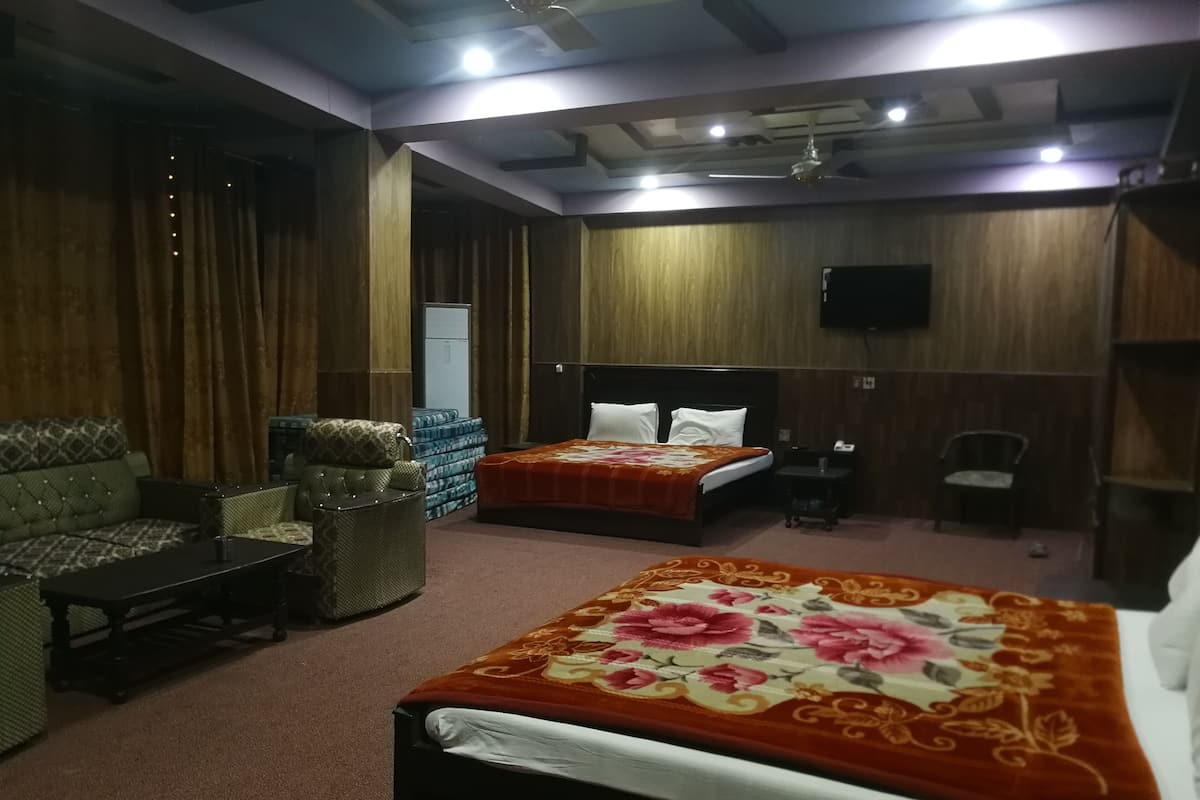 Ein Hotelzimmer mit zwei Betten, einem Schlafsofa, einem Sessel und einem Fernseher.