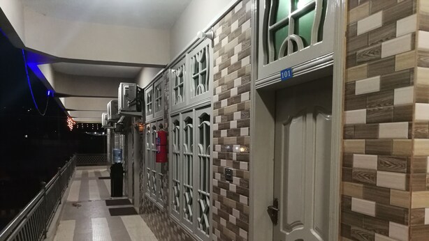 Un couloir aux murs recouverts de carreaux, une porte portant l’inscription « 101 », et un distributeur d’eau.