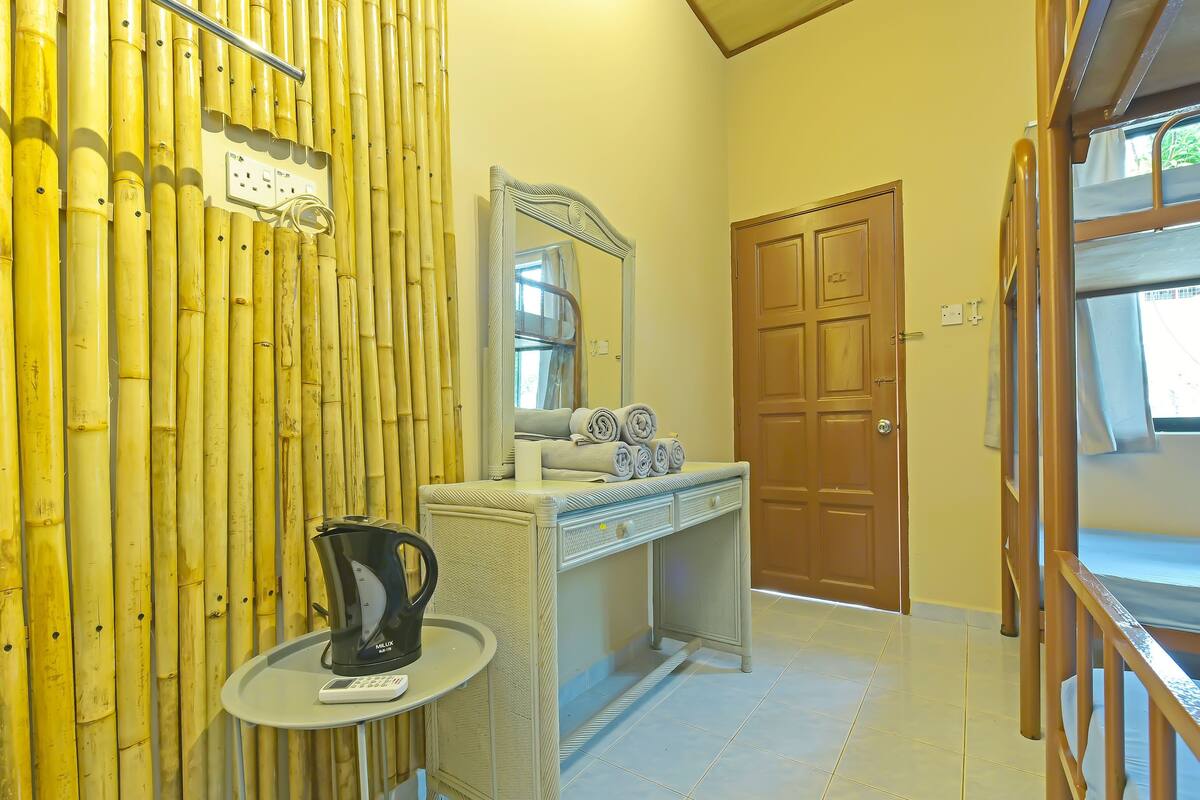 A bathroom with a bamboo wall, a sink with towels, a mirror, and a door.