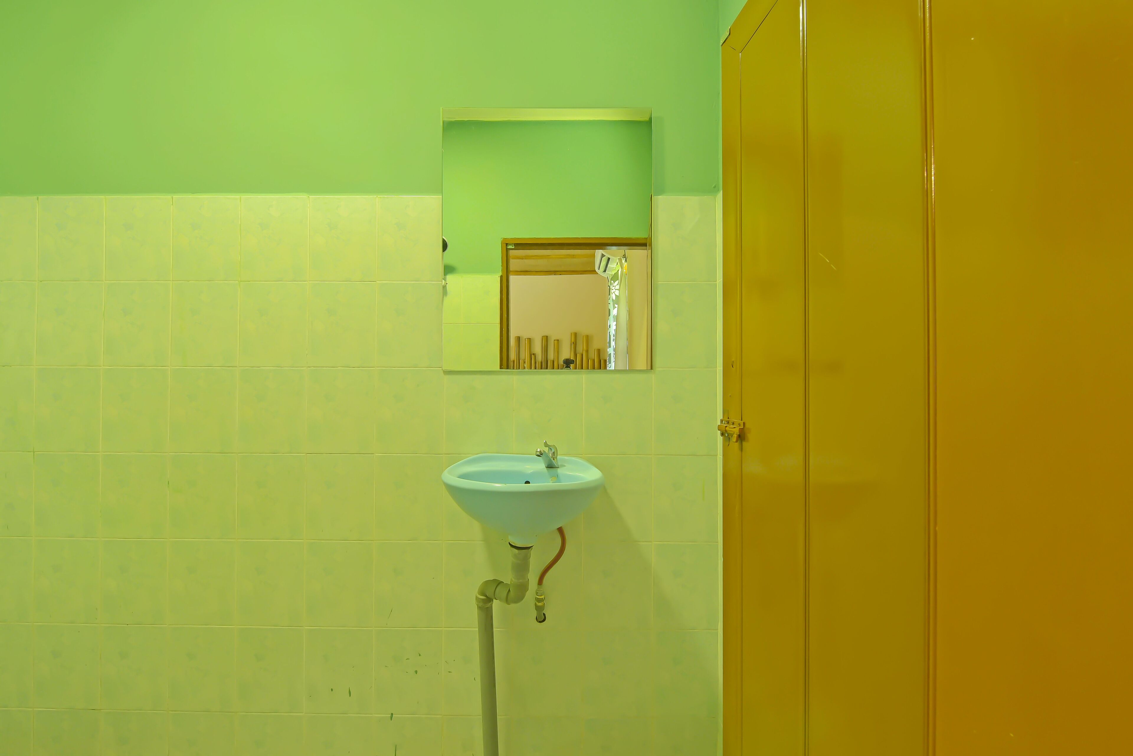 A bathroom with a sink, mirror, and yellow door.
