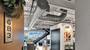 Ein modernes Interieur mit einem polierten Betonboden, einer Holztür mit einem Schild, einer Treppe und einem an der Wand befestigten Schild mit der Aufschrift 'hello'.