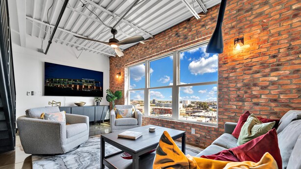 Ein modernes Wohnzimmer mit großem Fenster, Deckenventilator und flachbildschirm-Fernseher an der Wand.
