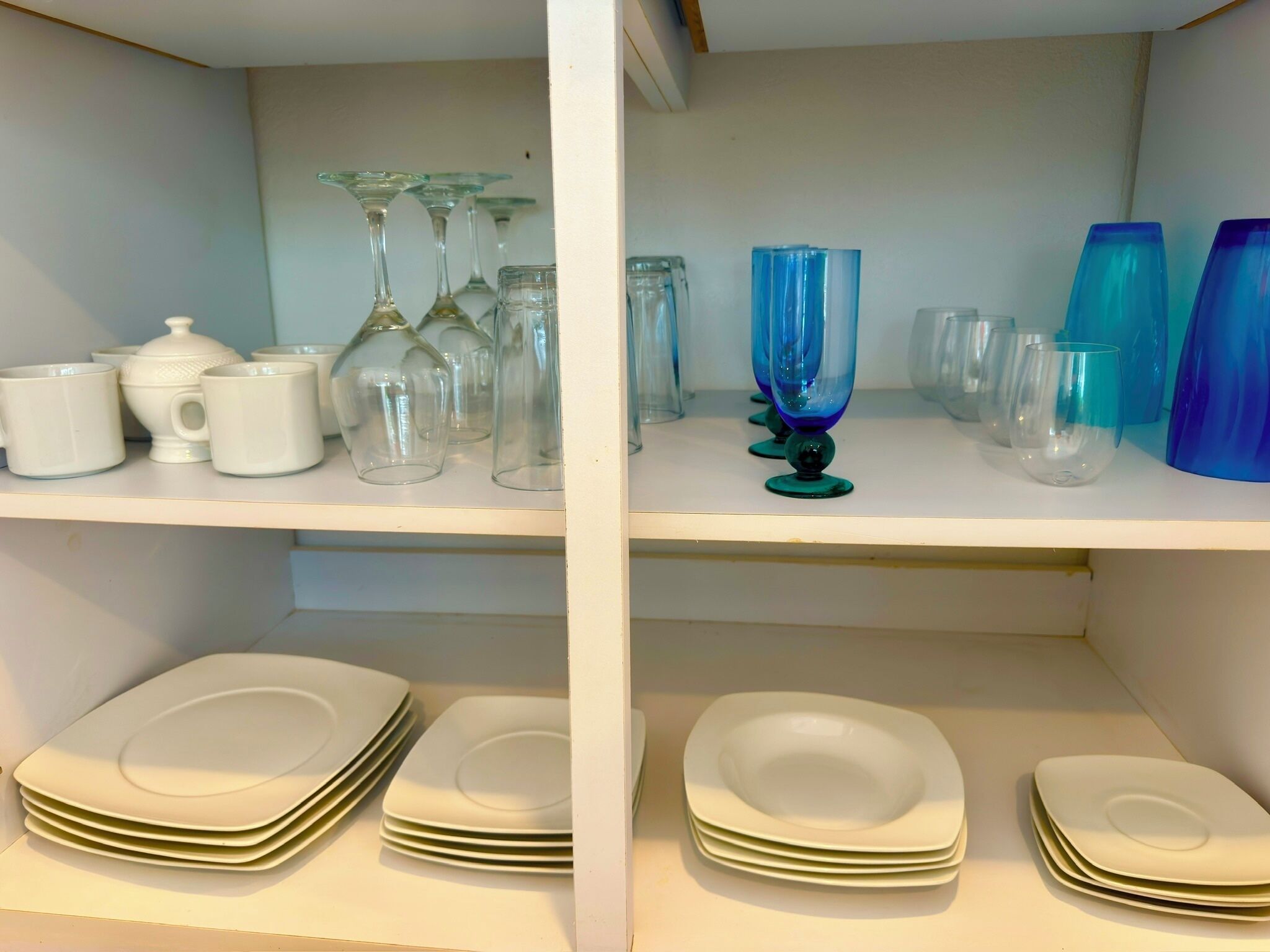 A storage area with shelves containing various glassware and plates.