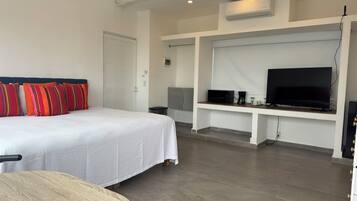 Ett hotellrum med en säng, en tv, ett skrivbord och en kaffebryggare.