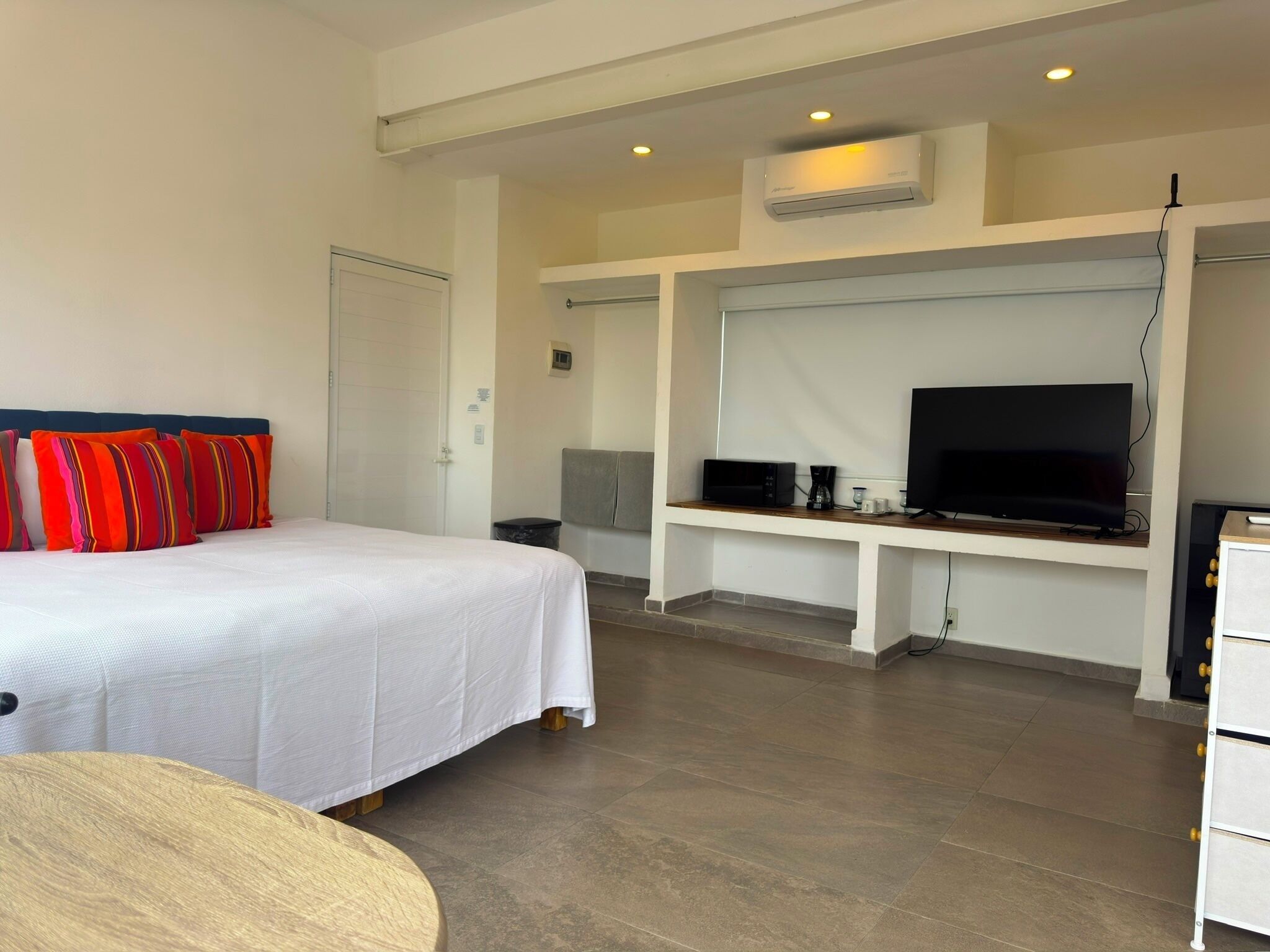 Una habitación de hotel con cama, televisión, escritorio y aire acondicionado.
