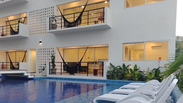 Ein modernes Hotel mit Poolbereich, ausgestattet mit weißen Liegestühlen und einem klaren, blauen Pool.