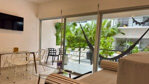 Ein Balkon mit einer Hängematte, einem Glastisch und Stühlen.