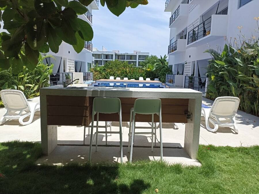 Een buitengedeeltelijke bar met twee groene stoelen en een pooltafel.