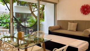 Ein modernes Wohnzimmer mit Glastisch, weißen Stühlen, einer Couch und einem Deckenventilator.