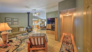 A spacious living room with a sofa, armchair, and coffee table, a kitchen in the background, and a hallway leading to a door. - Montana Home on 5 Acres: Near Lake Koocanusa! (Rexford)