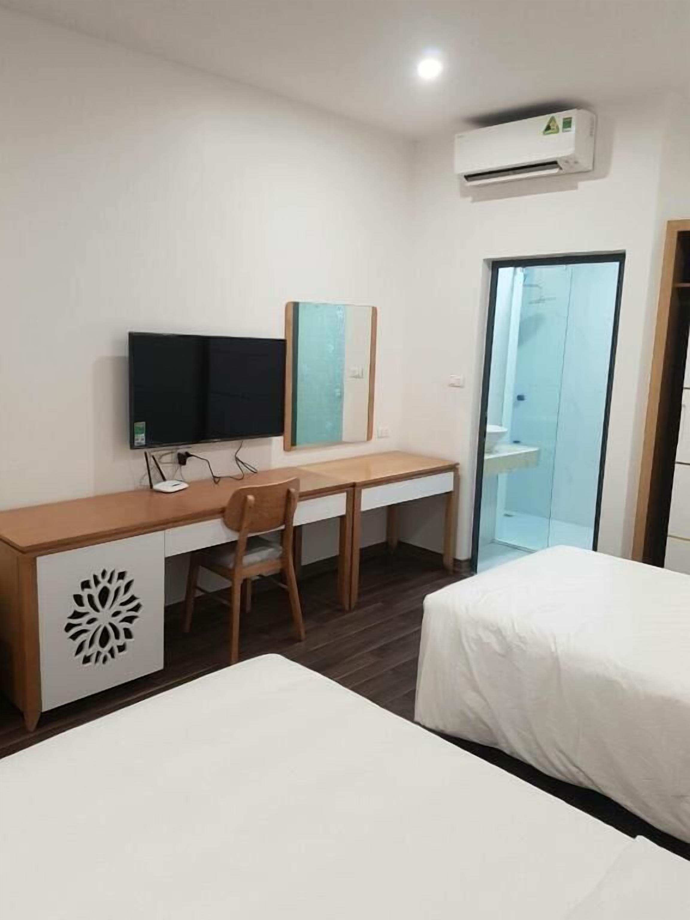 Une chambre d’hôtel équipée d’un bureau, de deux lits, d’une télévision et d’un appareil de climatisation.