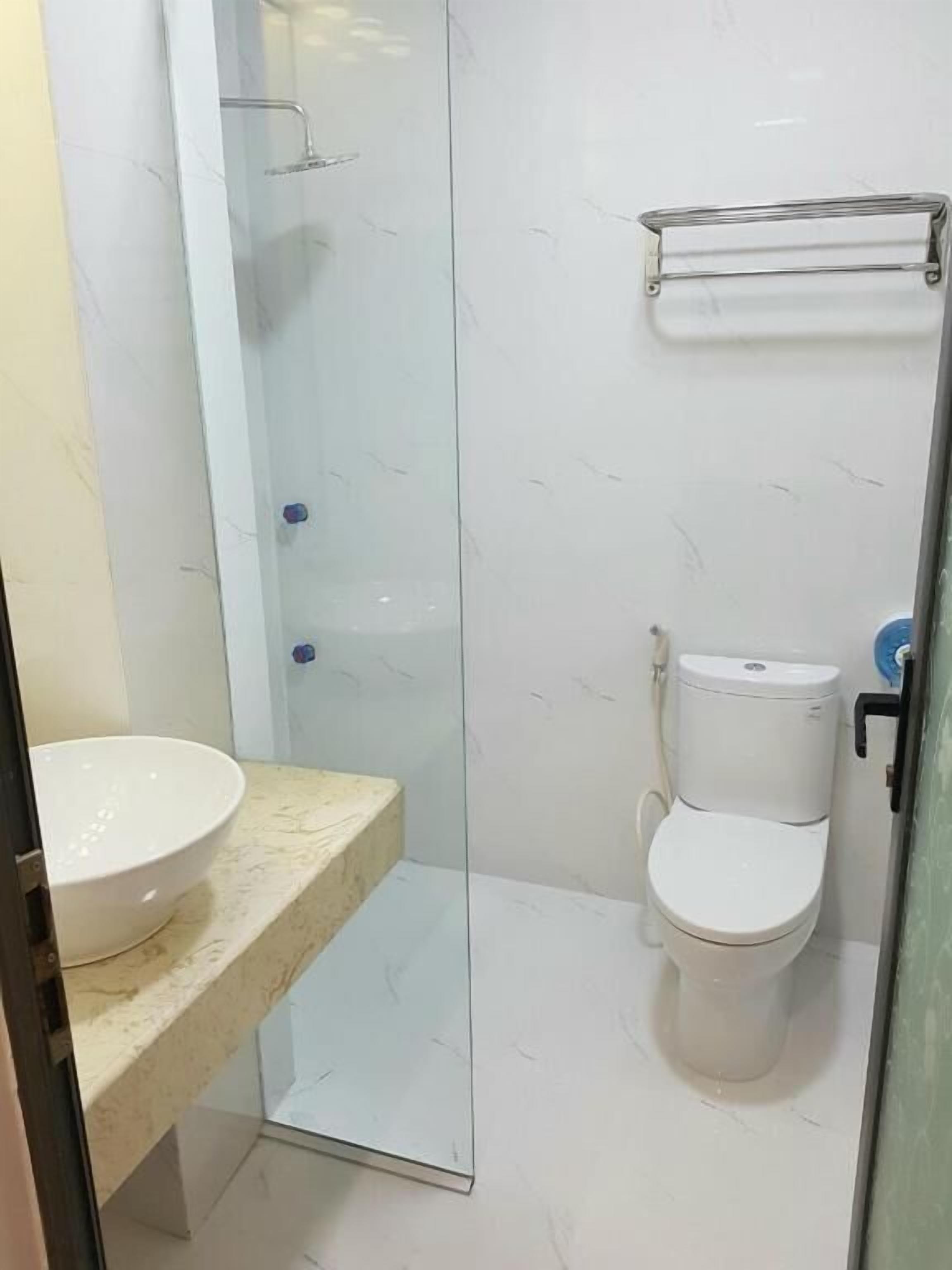 A bathroom with a glass-enclosed shower, a toilet, and a sink.