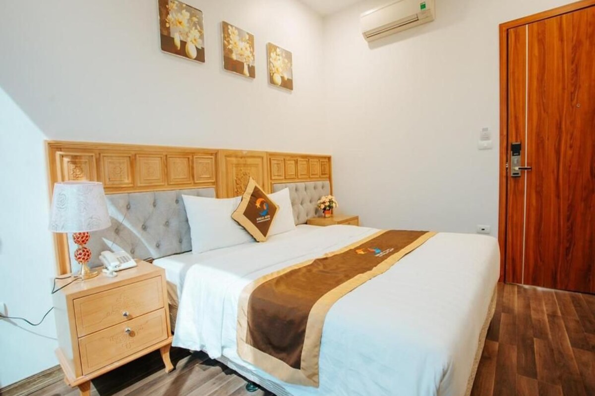 A neatly arranged bedroom with a wooden headboard, a bedside table with a lamp, and a bed with a brown throw blanket.