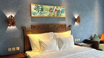 A neatly made bed with white linens, a wooden headboard, and a tropical-themed painting above it.