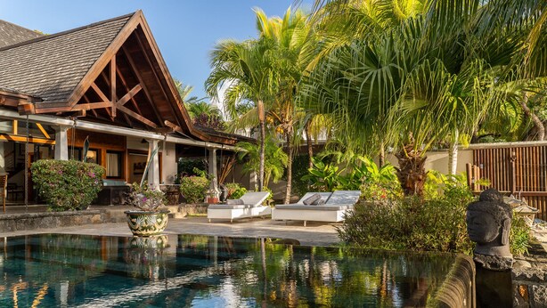 A pool with lounge chairs, a wooden building, and tropical plants. - Villa Matahari by muse villas (Black River)