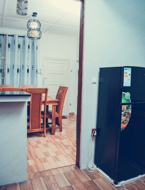 Enjoy meals in this cozy kitchen with a dining table and chairs, refrigerator, and hanging light fixture.