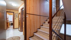 Una escalera con paredes de madera y suelo de baldosas que conduce a un nivel superior.