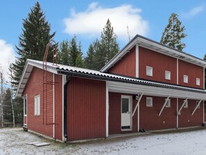 A red two-story building with a covered porch and a door. - Lomakatti 10b by Interhome (Sotkamo)