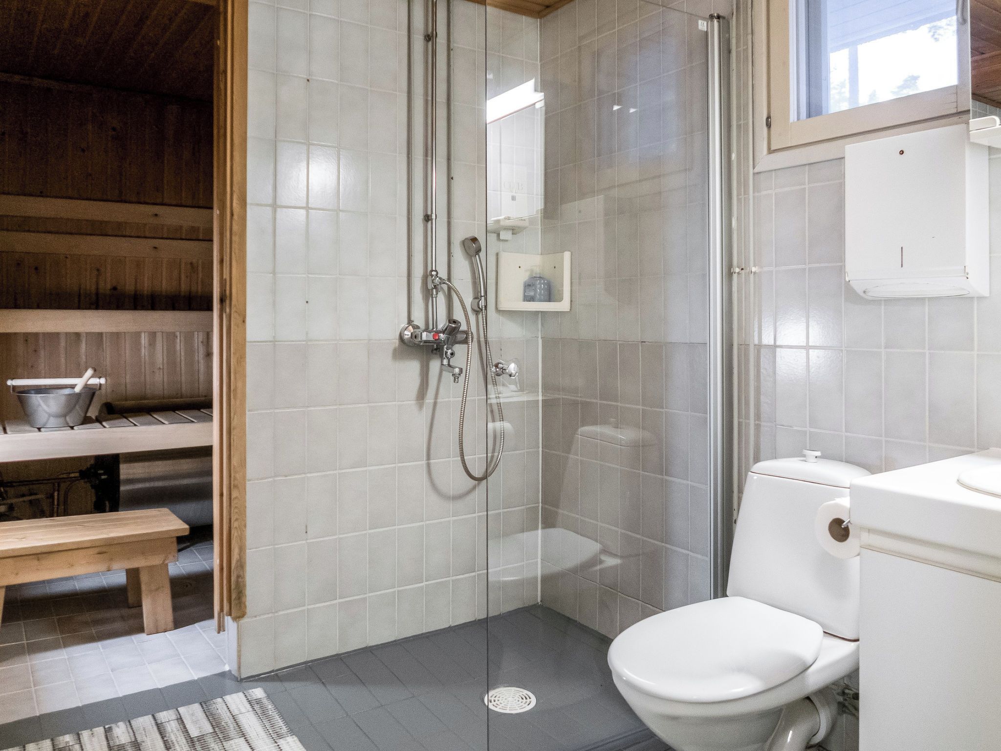 Ein Badezimmer mit Dusche, Toilette und einer Sitzbank.