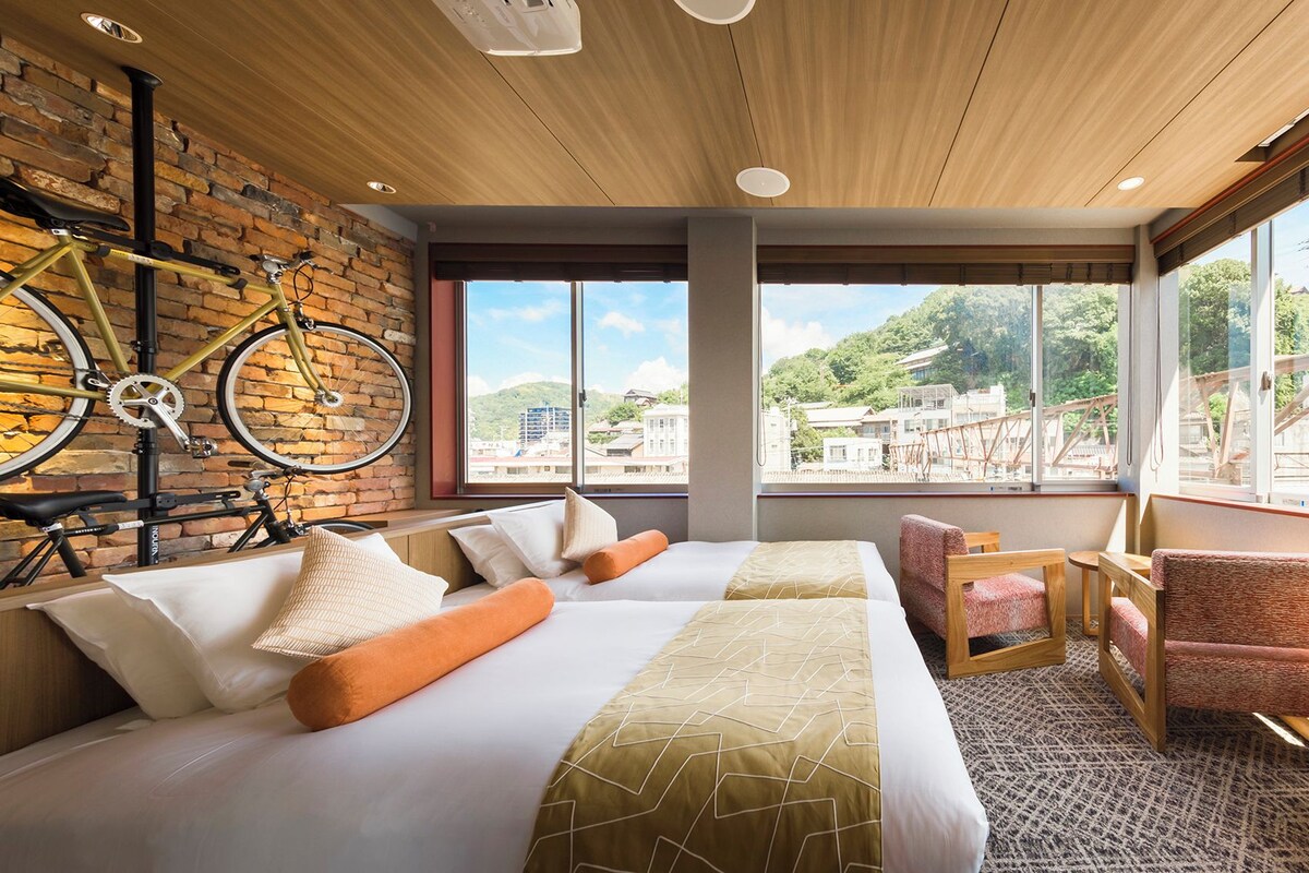A hotel room with a bed, a seating area, and a view of the outside.